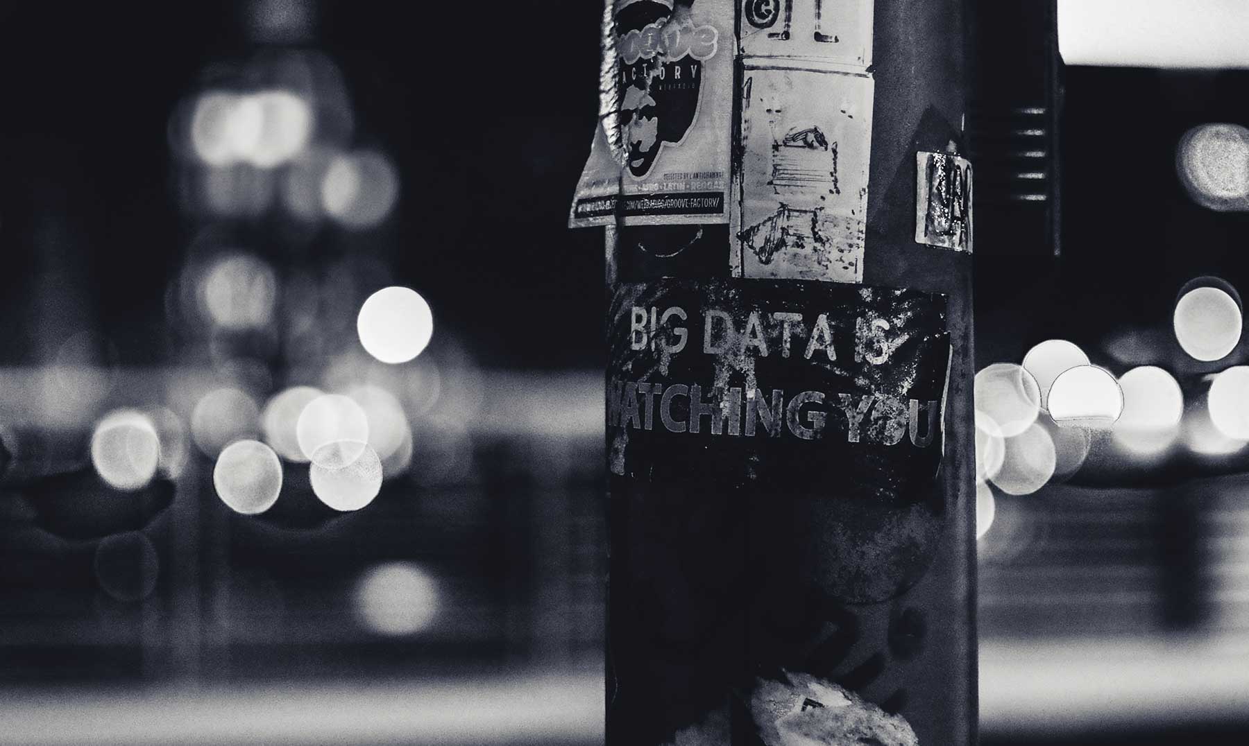 night time, city lights in the background, at night, showing a telephone post with text saying 'big data is watching you'